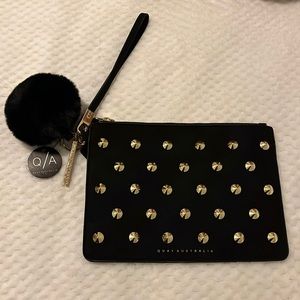 Quay Studded Wristlet Clutch with Pom Pom in Black/Gold